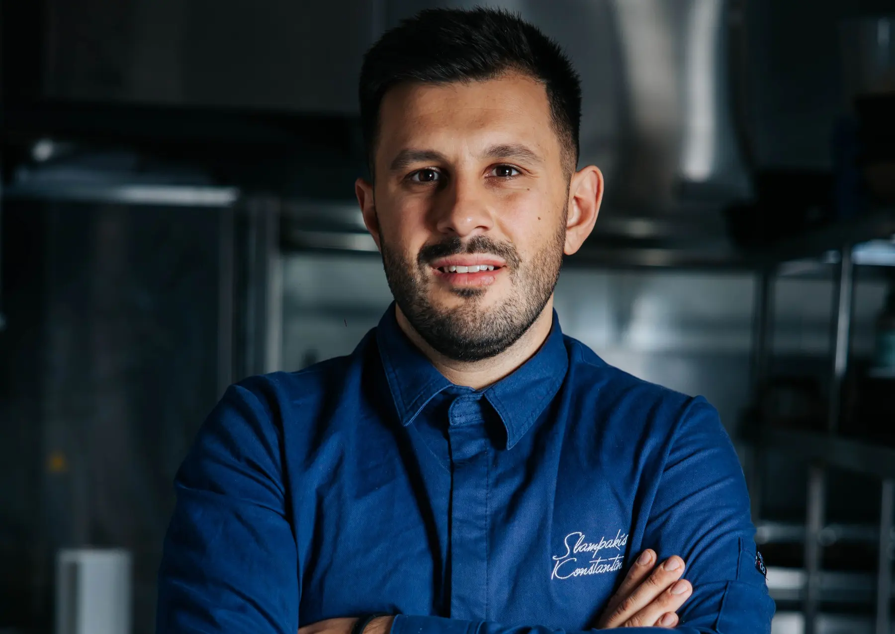 Ο Κωνσταντίνος Σλαμπάκης με μπλε σακάκι chef στην κουζίνα